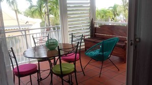Een balkon met een houten tafel en stoelen, een groene stoel en een bank.