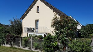 A two-story building with a balcony, a window, and a door. - furnished apartment with all mod cons in a detached house with a garden (Bagnoles-de-l'Orne)