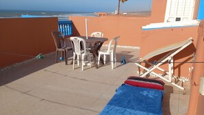 A terrace with a table and chairs, a blue towel, and a satellite dish. - Town house in Aglou Plage "chez Laurent": Ocean and Mountain  (Unknown)