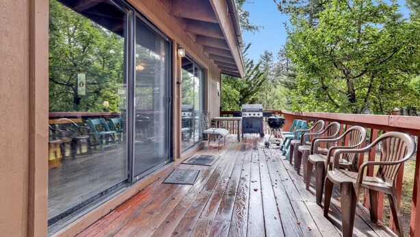 A wooden deck with outdoor seating and a barbecue grill.