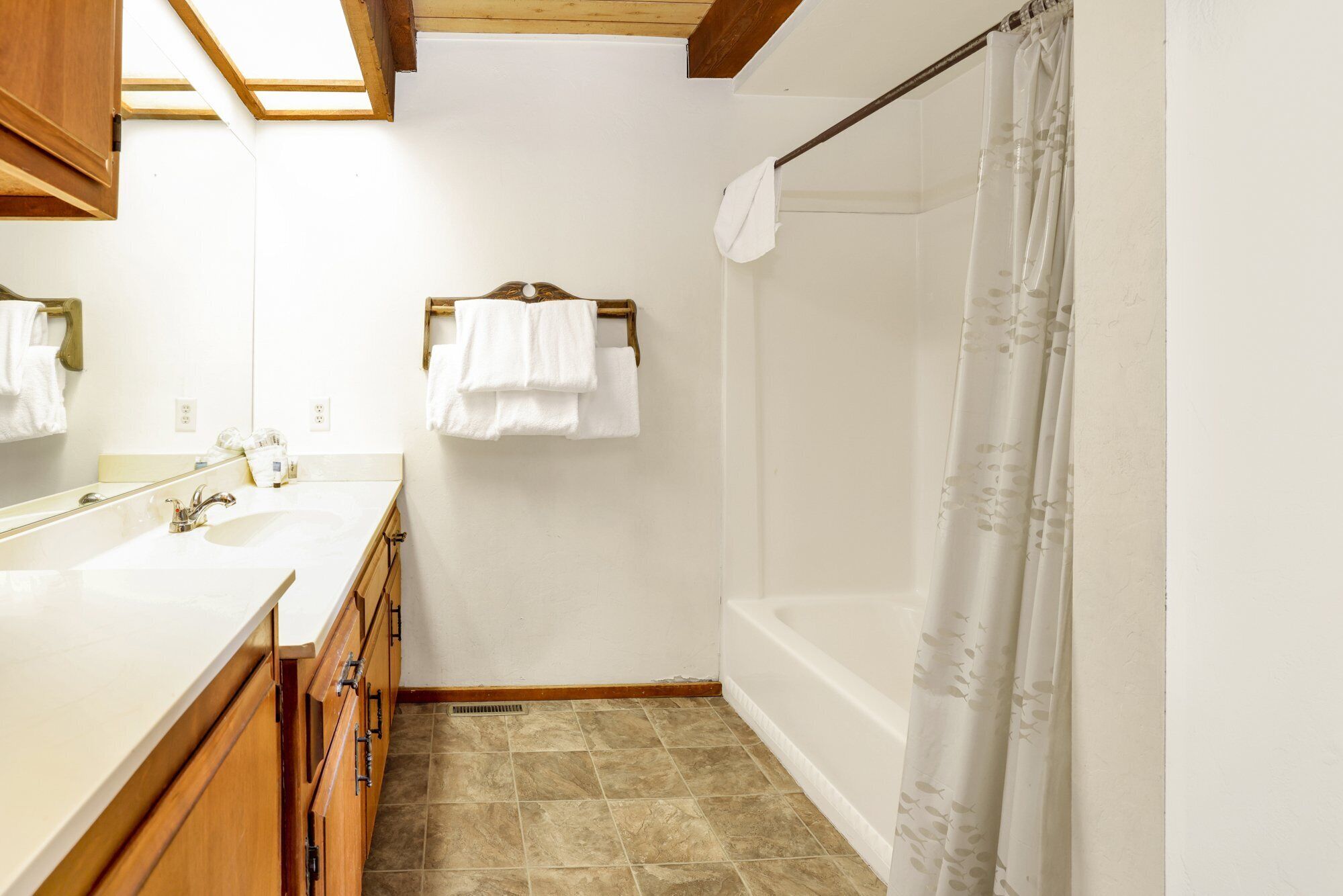 Une salle de bain avec une baignoire, un rideau de douche, un lavabo et un miroir.