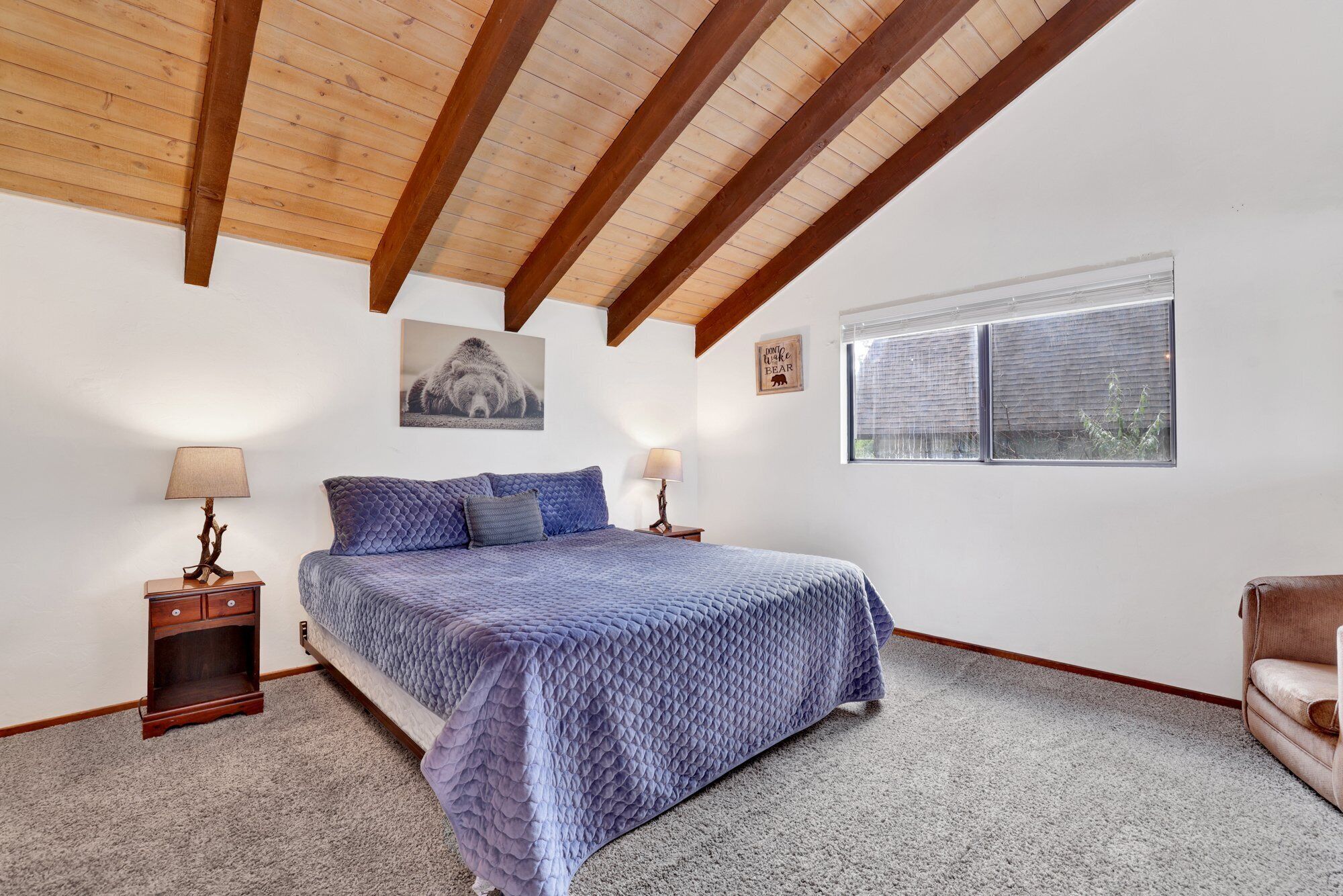 Een slaapkamer met een bed, twee nachtkastjes, een raam en een beren-thema decoratie aan de muur.