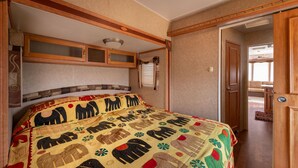 Une chambre à coucher avec un grand lit, une tête de lit en bois et une porte donnant sur une autre pièce.
