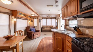 Une cuisine compacte pour camping-car, équipée d’une cuisinière, d’un évier et de placards en bois.