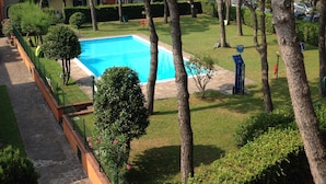 Uma piscina rodeada por árvores e um edifício com varandas.