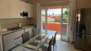 Uma cozinha moderna com mesa de jantar de vidro, eletrodomésticos de aço inoxidável e vista para o exterior.