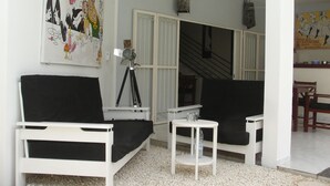 Un salon avec des meubles blancs, un trépied et un tableau accroché au mur.