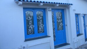 A building with blue doors and windows, white walls, and a tiled roof.