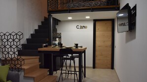 A modern kitchen with a wooden table, black stools, and a staircase leading to an upper level.