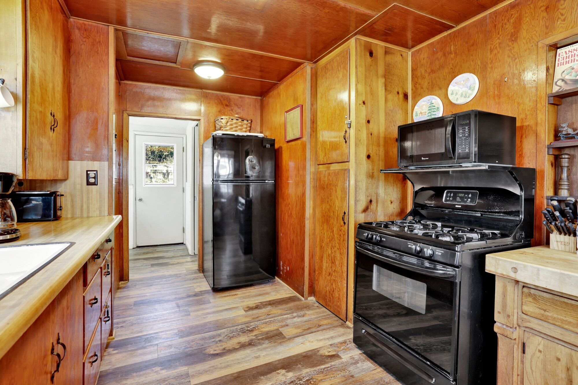 Una cocina con armarios de madera, un refrigerador, una estufa y un microondas.