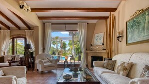 Uma sala de estar ampla com uma janela grande, lareira e vista para a piscina.