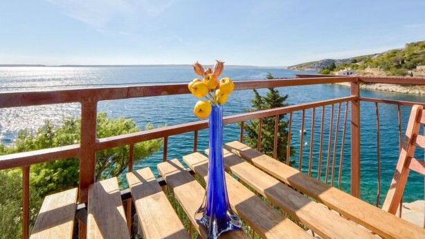 A wooden deck with a railing overlooking a body of water and a distant shoreline.
