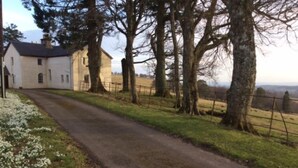 A rural road with a white building on the left, surrounded by trees and a grassy area. - Wester Riechip by Interhome (Dunkeld)