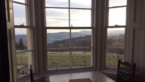 A room with a table and chairs, large windows with a view of a field and mountains. - Wester Riechip by Interhome (Dunkeld)
