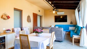 A living room with a dining table, chairs, a sofa, and a ceiling fan. - villa Erika 8 (Cagliari)