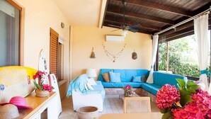 A cozy living area with a blue sofa, a wooden table, and a ceiling fan. - villa Erika 8 (Cagliari)