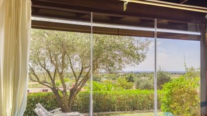 A room with a large window overlooking a garden and a view of the countryside. - villa Erika 8 (Cagliari)