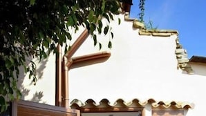 A bathroom with a blue-tiled shower, wooden doors, and a small garden area with grass and stepping stones. - villa Erika 8 (Cagliari)