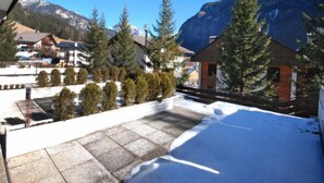 A snow-covered balcony with a view of a mountain range and buildings in the background. - Monti Pallidi by Interhome (Canazei)
