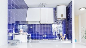 A modern kitchen with blue tiles, white cabinets, and a central island with chairs. - Apartment Symar by Interhome (Roses)