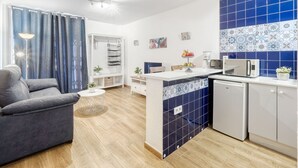 A compact living space with a kitchenette, a grey sofa, a small round coffee table, and a blue curtain. - Apartment Symar by Interhome (Roses)