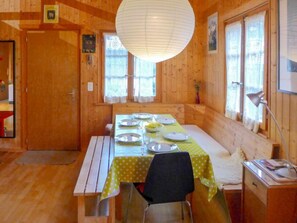 Enjoy meals in this inviting dining area with a long table set for a meal, a single chair, and a lamp for added lighting.