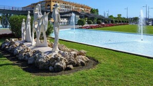 A swimming pool with a fountain, surrounded by rocks and grass, with a building in the background. - Mirador II by Interhome (Marbella)
