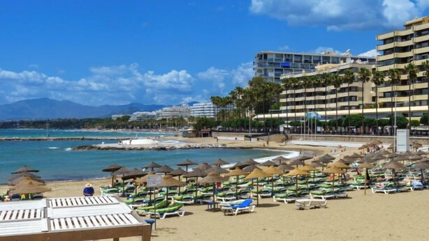 A beach with sun loungers, umbrellas, and a hotel in the background. - Mirador II by Interhome (Marbella)