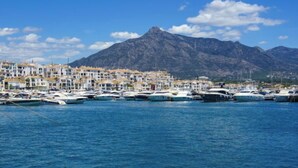 A marina with boats docked, a coastal town with white buildings, and mountains in the background. - Mirador II by Interhome (Marbella)