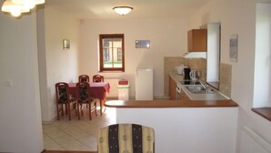 A compact kitchen with a dining area, a refrigerator, and a window.