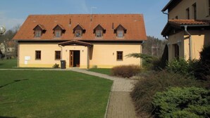 A two-story building with a tiled roof, a central entrance, and a small porch.