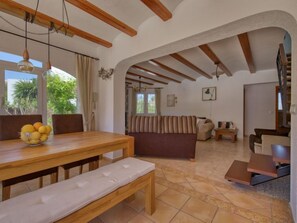 A spacious living area with a wooden dining table, benches, and a sofa.