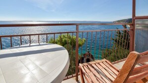 Een balkon met uitzicht op zee, een ronde tafel en een houten stoel.