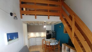 Una cocina compacta con comedor, una escalera de madera y un pequeño rincón de descanso.