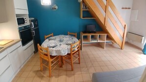 Una cocina compacta con una mesa de comedor, sillas de madera, un microondas y una estufa.