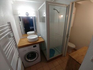 A compact bathroom with a washing machine, two sinks, a glass shower enclosure, and a toilet. - Rivages d'Olonne by Interhome (Les Sables d'Olonne)
