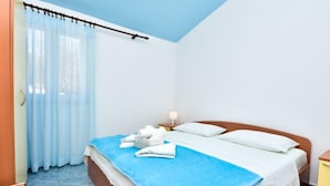 Une chambre d’hôtel avec un lit, une table de chevet, une lampe et une fenêtre avec des rideaux.
