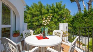 A round table with white chairs on a balcony, surrounded by greenery and a clear blue sky. - Florencia by Interhome (Jávea)