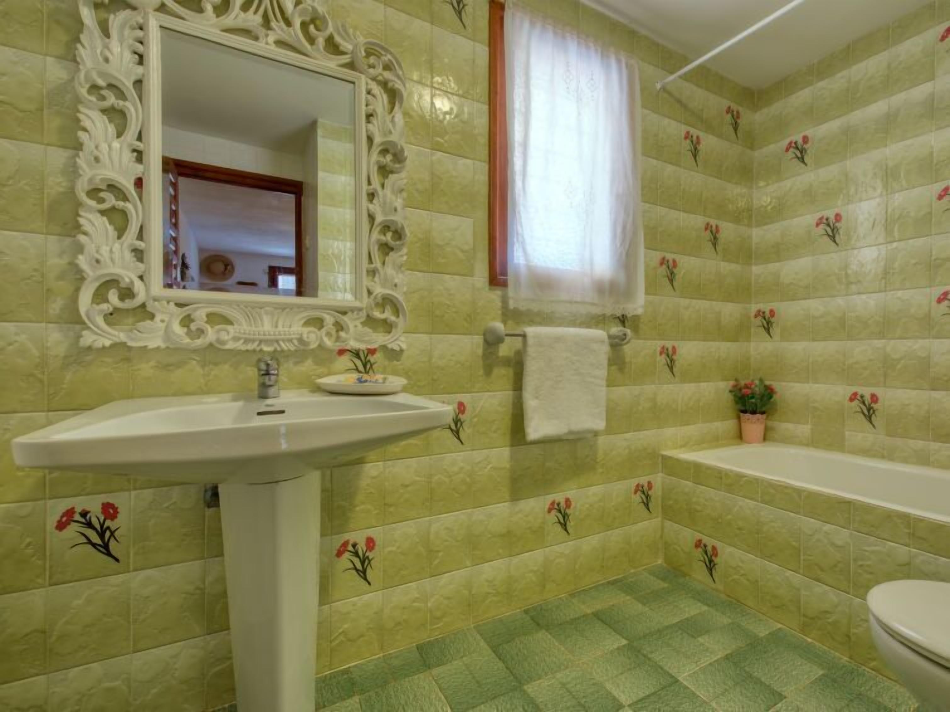 Une salle de bain équipée d’un lavabo, d’un miroir, d’une baignoire et de toilettes.