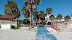 A beach path with palm trees, a blue mat, and a fence. - Beautiful condo for families, couples, and friends. (Madeira Beach)