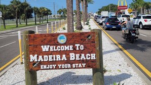 A welcome sign for Madeira Beach with a clear road and parked cars in the background. - Beautiful condo for families, couples, and friends. (Madeira Beach)
