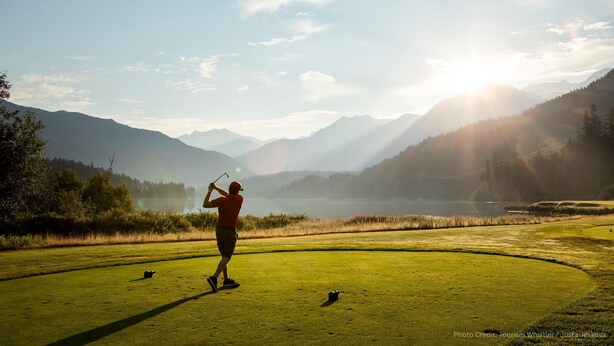 A golf course with a clear view of the surrounding mountains and a lake. - Cozy condo w/ hot tub & fireplace near lifts (Whistler)
