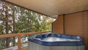 A hot tub on a balcony with wooden railings and a view of trees. - Cozy condo w/ hot tub & fireplace near lifts (Whistler)