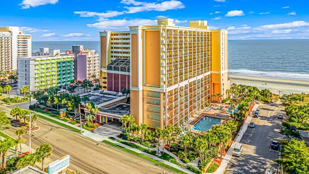 A hotel with multiple floors, a pool, and a beach view.
