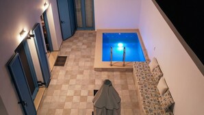 Una piscina interior pequeña con suelo de baldosas y una escalera.