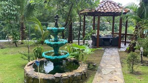A garden with a stone fountain, a gazebo, and a stone pathway.