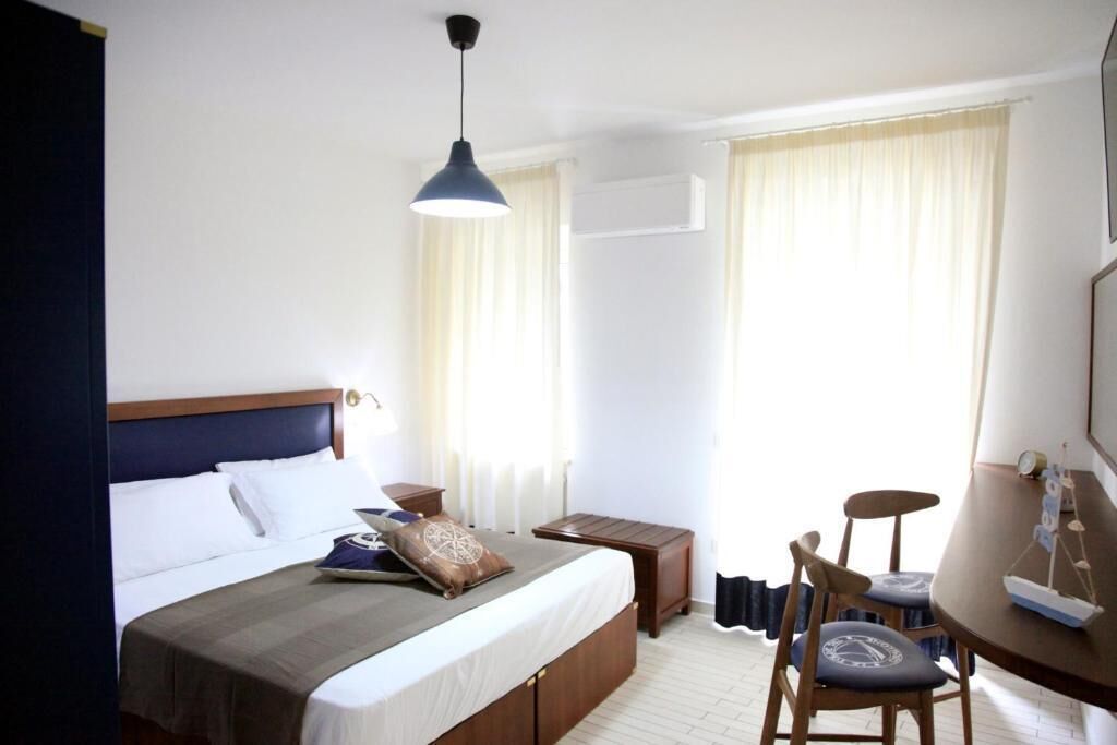 Une chambre d’hôtel comprenant un lit, une table de chevet, une chaise et un bureau avec une autre chaise.