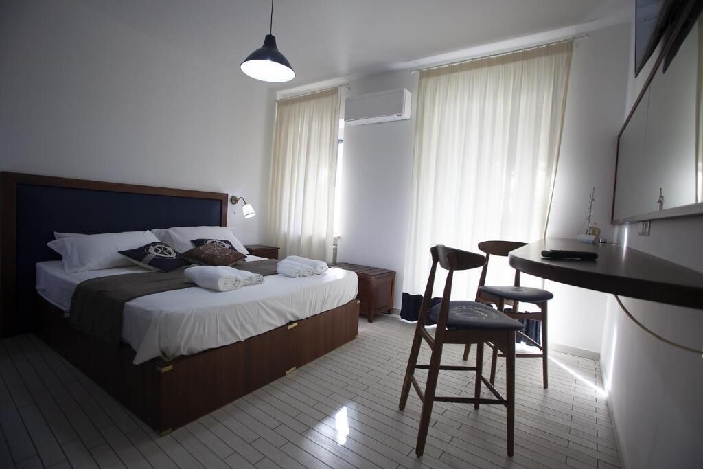 Een hotelkamer met een bed, nachtkastje, stoel en bureau met stoel.