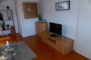 A living room with a wooden entertainment unit, a glass coffee table, and a flat-screen TV. - Apartment Wörth with a great view - Apartment in Wörth with a view (Wörth am Rhein)