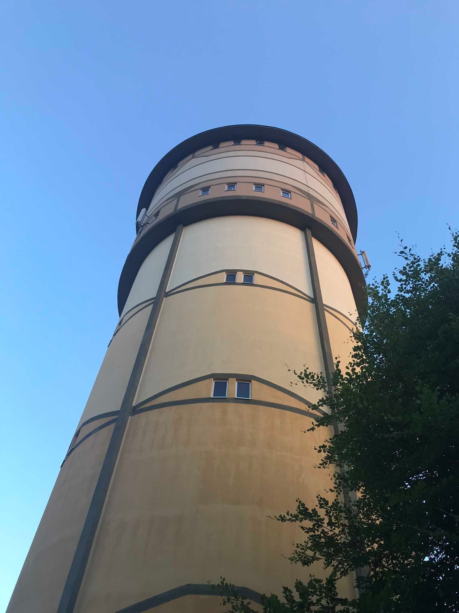 Un château d’eau cylindrique, surmonté d’une partie arrondie et doté de fenêtres.